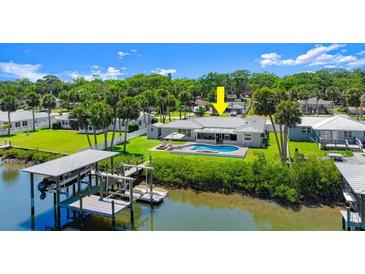 An inviting home with a pool, private boat lift and dock, all set against a lush, green backdrop at 5809 Riverside Dr, Port Orange, FL 32127