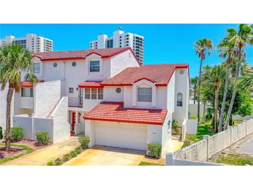 Beautiful multi-level home featuring red-tiled roof, a two-car garage and mature palm trees in the front yard at 200 Florida Shores Blvd, Daytona Beach, FL 32118