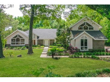 Charming home featuring a lush green lawn, mature trees, and unique architectural details at 530 Estates Pl, Longwood, FL 32779