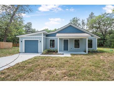 Charming single-story home featuring a front-facing garage and covered porch at 5620 Ridgewood Ave, De Leon Springs, FL 32130