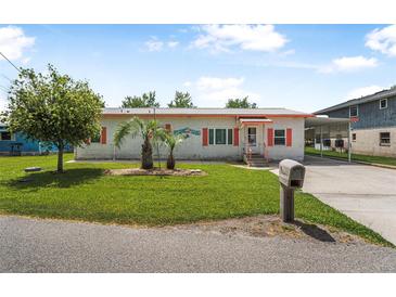 Charming single-story home with vibrant landscaping, brick facade, and covered parking at 24538 Wildhog Rd, Astor, FL 32102