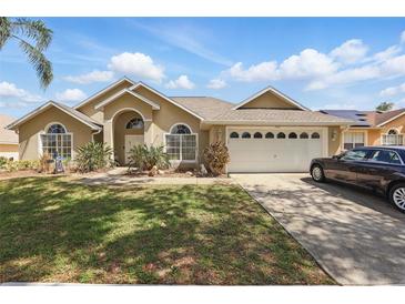 Inviting one-story home with a well-manicured lawn, arched windows, and an attached two-car garage at 1956 Southern Dunes Blvd, Haines City, FL 33844