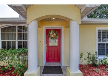 Charming red front door with decorative wreath, flanked by classic columns and lush landscaping at 1465 Admrial Nimitz Ave, Daytona Beach, FL 32124