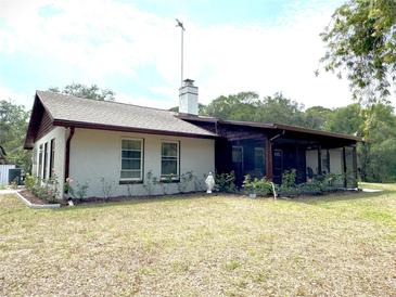 Charming single-story home with a screened porch, chimney, and landscaped flowerbeds under a cloudy sky at 486 S Us Highway 1, Oak Hill, FL 32759