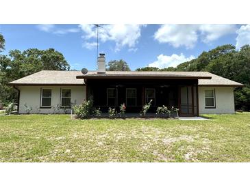 Home featuring a cozy, covered patio with ceiling fans and rose bushes; perfect for outdoor relaxation at 486 S Us Highway 1, Oak Hill, FL 32759