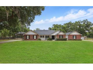 Charming single-story brick home with a well-manicured lawn and mature trees at 5865 Ross Creek Rd, Lakeland, FL 33810