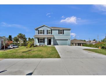 Two-story home features a large driveway, well-manicured lawn, and blue siding against a bright blue sky at 3828 S Atlantic Ave, Daytona Beach, FL 32118