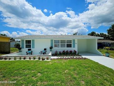 Charming single-story home with a well-manicured lawn and inviting curb appeal with chairs on the front patio at 68 Hibiscus Dr, Ormond Beach, FL 32176