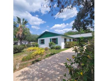 Charming home with green trim, a landscaped yard and long driveway leading up to the carport at 741 Ellen St, Daytona Beach, FL 32114