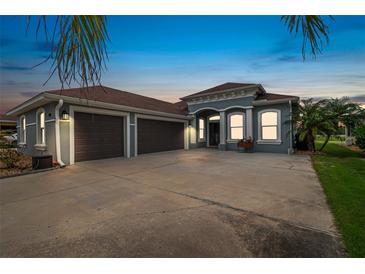 Charming home featuring a three-car garage, a well manicured lawn and lovely tropical landscaping at 3345 Tesoro Cir, New Smyrna Beach, FL 32168