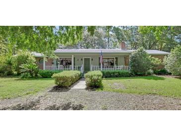 Charming single-story home with a welcoming front porch, beautiful landscaping, and an American flag at 3720 Willow Ave, Deland, FL 32720