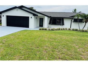 Charming single-story home with a well-manicured lawn, black trim, and a black garage door at 992 Shockney Dr, Ormond Beach, FL 32174