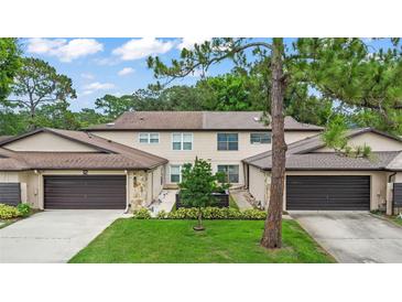 Charming townhome featuring an attached garage, well-maintained lawn, and beautiful landscaping at 12 Big Buck Trl, Ormond Beach, FL 32174