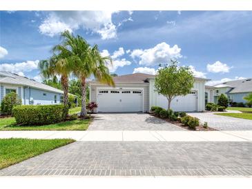 Charming exterior view of a home with a brick driveway, lush landscaping, and a two-car garage under a sunny sky at 206 St Somewhere Dr, Daytona Beach, FL 32124