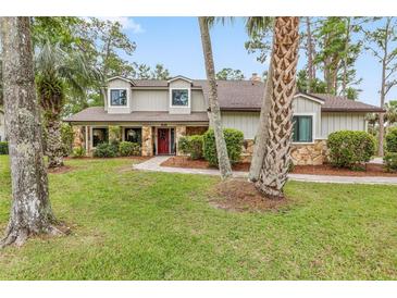 Charming home featuring a stone facade, well-manicured lawn, and inviting landscaping at 428 Pelican Bay Dr, Daytona Beach, FL 32119