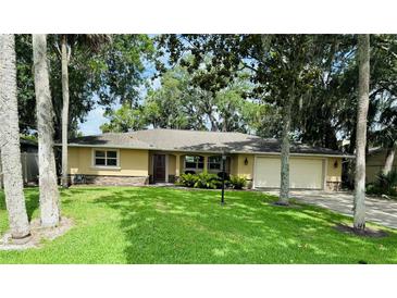 Charming single-story home with a well-manicured lawn, beautiful landscaping, and an attached two-car garage at 480 Palm Ave, Ormond Beach, FL 32174