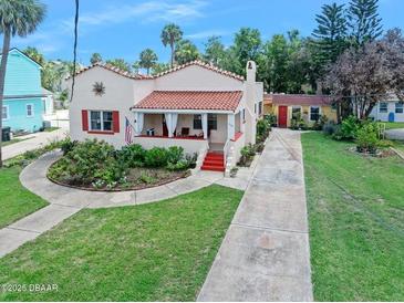 Charming single-story home featuring a beautiful red tile roof, covered porch, and meticulously maintained landscaping at 918 N Wild Olive Ave, Daytona Beach, FL 32118