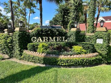 Welcoming Carmel entrance sign with lush greenery, brick accents, and clear blue sky at 1162 Carmel Cir # 100, Casselberry, FL 32707