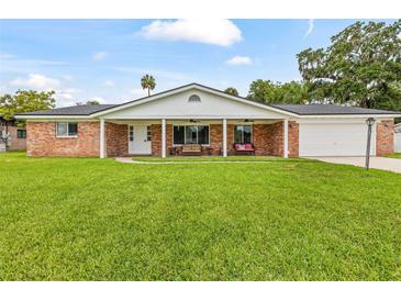 Charming red brick home with a covered front porch and a large, well-manicured lawn at 950 Pineapple Rd, South Daytona, FL 32119