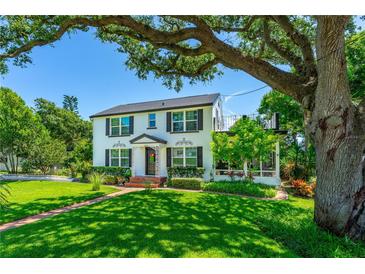 Charming two-story home featuring a well-manicured lawn, mature trees, and an inviting brick walkway to the front door at 1221 Gamble Pl, Daytona Beach, FL 32118