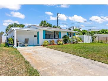 Charming single-story home featuring a well-maintained lawn, cozy carport, and vibrant turquoise shutters at 1 Beechwood Dr, Ormond Beach, FL 32176