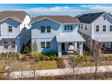 Two-story light blue house with metal roof, front porch, and landscaped yard at 13438 Leggett Aly, Orlando, FL 32827