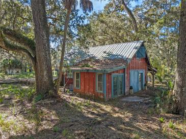 Rustic, two-story home with a metal roof, nestled among trees offering a unique, secluded setting at 13524 Corkwood Ln, Astatula, FL 34705