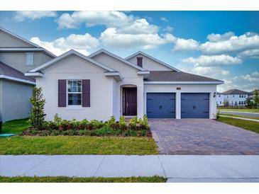 Two-car garage, light beige house with dark shutters and landscaping at 13200 Peaceful Melody Dr, Winter Garden, FL 34787
