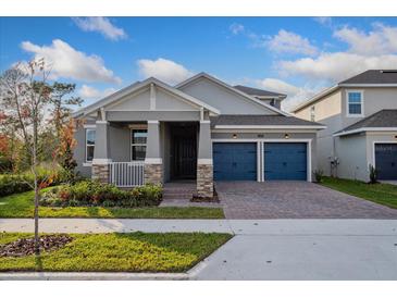 Two-story house with gray siding, blue garage doors, and landscaping at 13230 Peaceful Melody Dr, Winter Garden, FL 34787