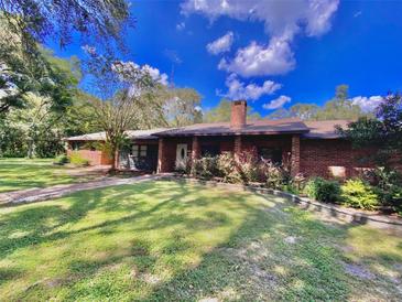 Charming single-story brick home with a well-manicured lawn and mature landscaping at 1921 Smitty Rd, Lady Lake, FL 32159