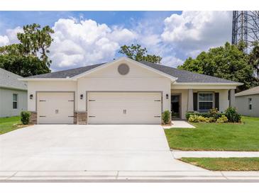 Charming single-story home featuring a three-car garage, well-manicured lawn, and beautiful landscaping at 6834 Mossy Oak Ln, Lakeland, FL 33810