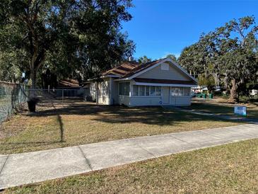 Tan house with a brown roof, green lawn, and sidewalk at 1010 S Grove St, Eustis, FL 32726