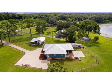 Stunning lake view property featuring a blue house, metal roof, spacious land, and a long drive way at 4114 Dove Valley Ln, Lady Lake, FL 32159