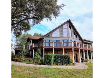 A-frame log home with wrap-around deck, stone accents, and landscaping at 26348 Se Highway 42, Umatilla, FL 32784