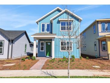 Charming two-story home with a blue exterior, white trim, a green front door and a brick walkway at 3106 Voyager Ave, St Cloud, FL 34771