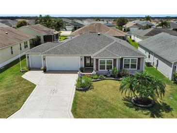 Charming single-story home featuring a well-manicured lawn, tropical landscaping, and a decorative driveway at 736 Jones Ln, The Villages, FL 32163