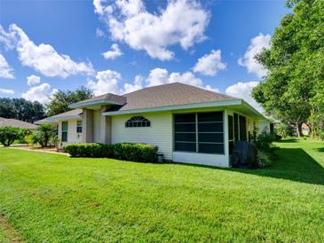 Well-maintained home with a spacious backyard, screened lanai, and lush green lawn at 21945 King Henry Ave, Leesburg, FL 34748