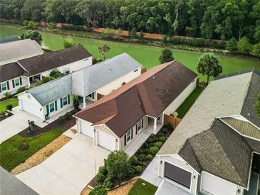 Aerial view of a single-Gathering home with a brown roof and a two-car garage, situated near a canal at 2492 Lay Ln, The Villages, FL 32163