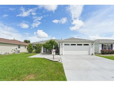 Single-story home with a two-car garage and well-manicured lawn at 1101 Blythe Way, The Villages, FL 32162