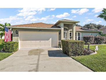 Charming single-story home featuring a well-manicured lawn and an attached two-car garage and beautiful landscaping at 1039 Sandhill St, Groveland, FL 34736