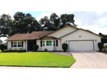 Charming single-story home featuring a manicured lawn and a brick-paved driveway leading to an attached two-car garage at 6410 Tildon Ct, Leesburg, FL 34748