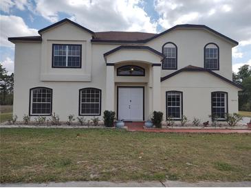 Charming two-story home with a well-manicured lawn, a white exterior, and black trim on the windows and roofline at 18744 Sabal St, Orlando, FL 32833