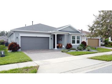 Charming single-story home with a two-car garage, brick driveway, and manicured landscaping at 518 Narrow View Ln, Groveland, FL 34736