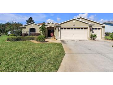 Charming single-story home featuring a well-maintained lawn, two car garage, and lush landscaping at 815 Forest Breeze Path, Leesburg, FL 34748