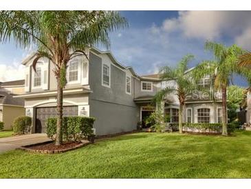 Charming two-story home with a well-manicured lawn and lush landscaping, including palm trees at 13412 Fox Glove St, Winter Garden, FL 34787