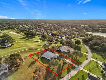 Stunning aerial view of a home on a golf course with mature trees and meticulously landscaped grounds at 36732 Barrington Dr, Eustis, FL 32736