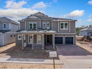 Two-story home with gray siding, two-car garage, and covered porch at 14256 Crest Palm Ave, Windermere, FL 34786