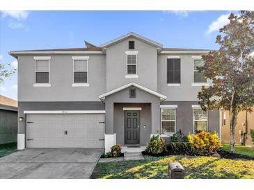 Two-story home featuring a neutral color scheme, attached garage, and well-maintained landscaping at 1961 Nations Way, Saint Cloud, FL 34769