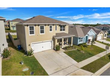 Two-story house with a beige exterior, white garage door, and landscaped front yard at 2011 Chickasaw Blvd, Davenport, FL 33837