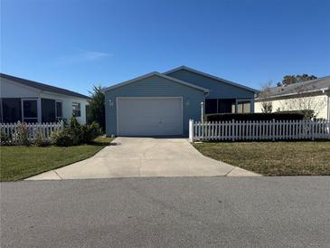 Cute light blue house with white picket fence and a two-car garage at 718 Villita Ln, Lady Lake, FL 32159